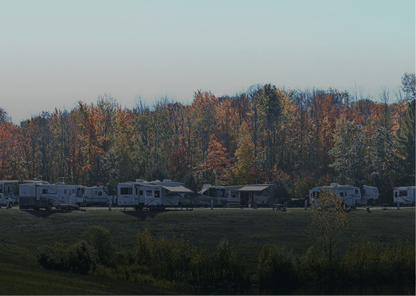 RVs parked near colorful autumn forest.