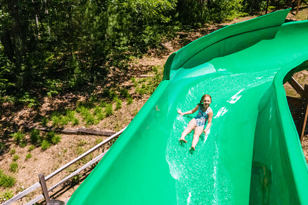 Child sliding down a green water slide.